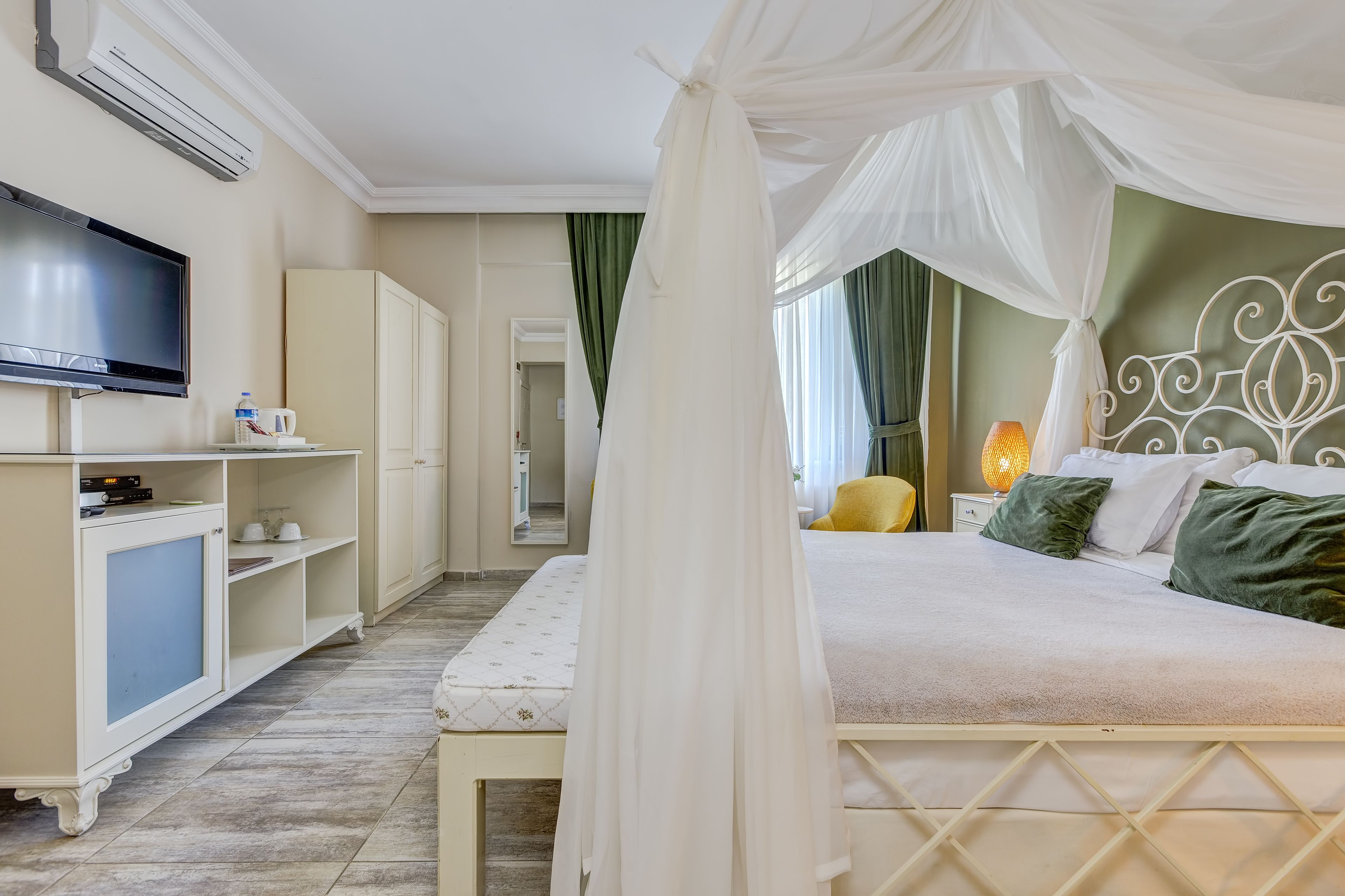 A bedroom with a bed, a TV, a wardrobe, and a bedside table with a lamp.