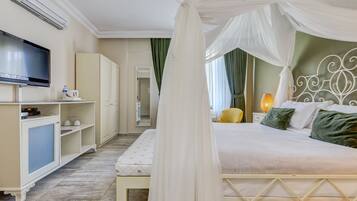 A bedroom with a bed, a TV, a wardrobe, and a bedside table with a lamp.