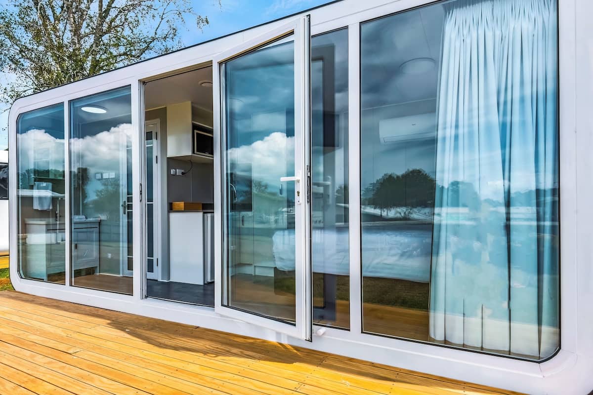 Una casa moderna de un piso con amplios ventanales correderos que dan a una cocina y zona de estar.