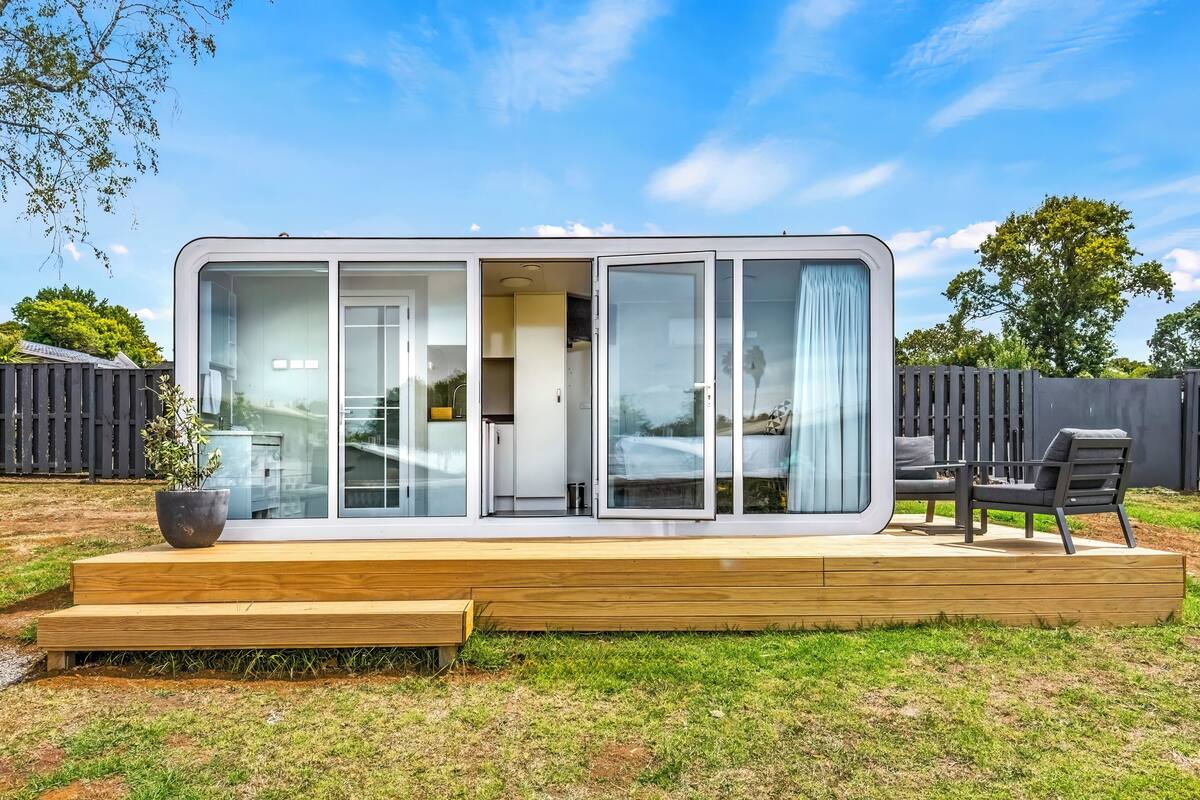 Una casa moderna de un piso con terraza, puertas correderas amplias de vidrio y un pequeño espacio de estar al aire libre.