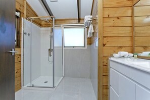 Une salle de bain moderne avec une douche à l’italienne en verre, des murs en bois et un meuble-lavabo blanc.
