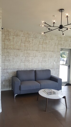 Un salon moderne avec un canapé gris, une table basse ronde et un mur à texture.
