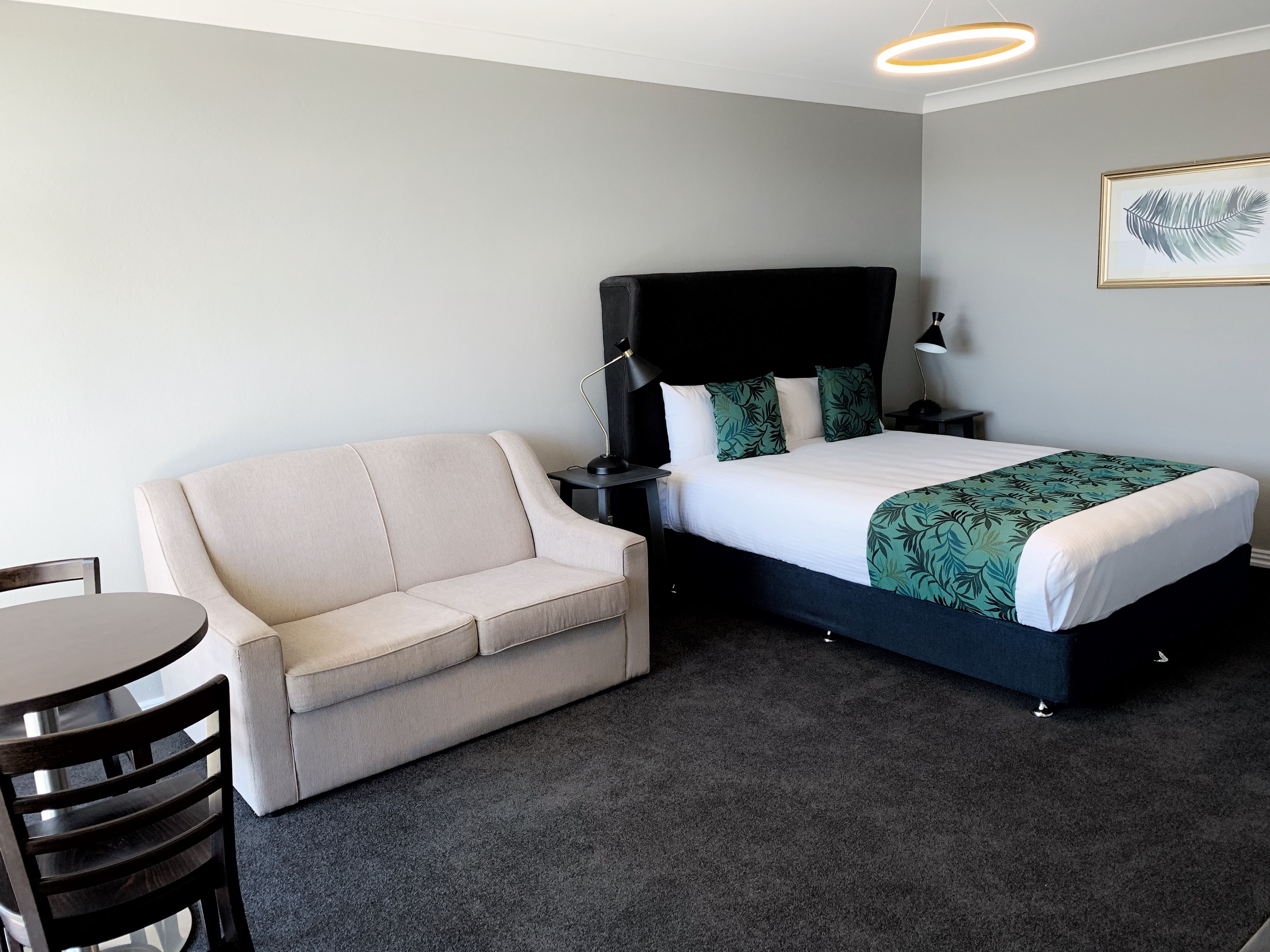 Una habitación de hotel con cama, sofá, una mesita y una silla.