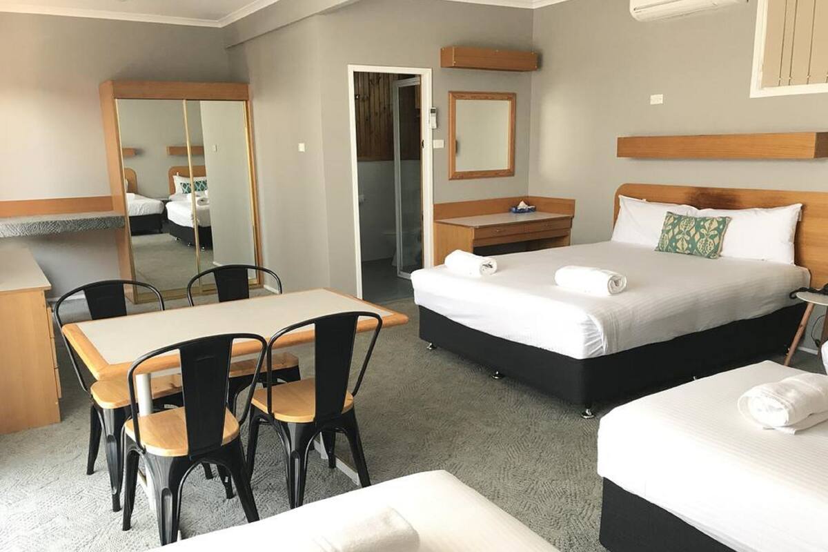 A hotel room with a bed, a desk, and a chair.