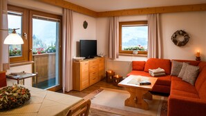 Een gezellige woonkamer met een bank, een televisie en een eethoek met een tafel gedekt voor twee personen.