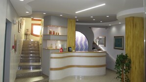 Un área de recepción con un mostrador curvo, una escalera y una planta en maceta.