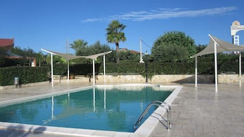 En säsongsöppen utomhuspool och solstolar