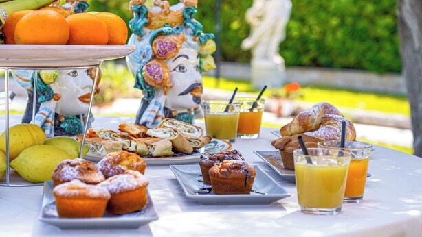 Una mesa con pasteles, frutas y jugo de naranja.