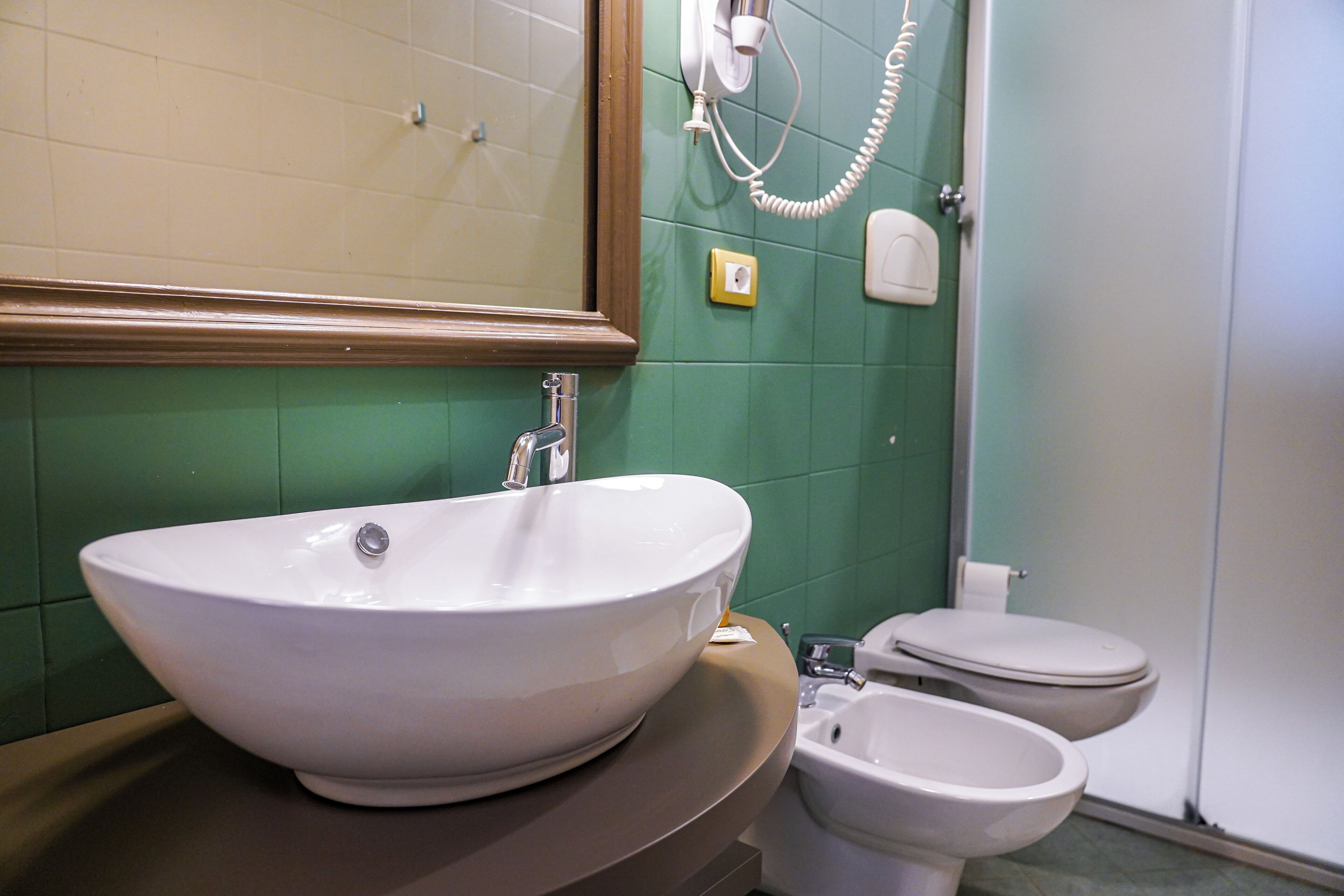 A bathroom with a large white sink, a toilet, and a bidet.
