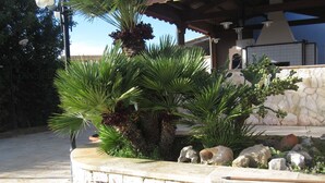 Un muro de piedra con plantas de palma y un banco de piedra.