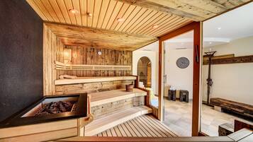 Eine Sauna mit hölzernen Bänken und einem sichtbaren Kamin.
