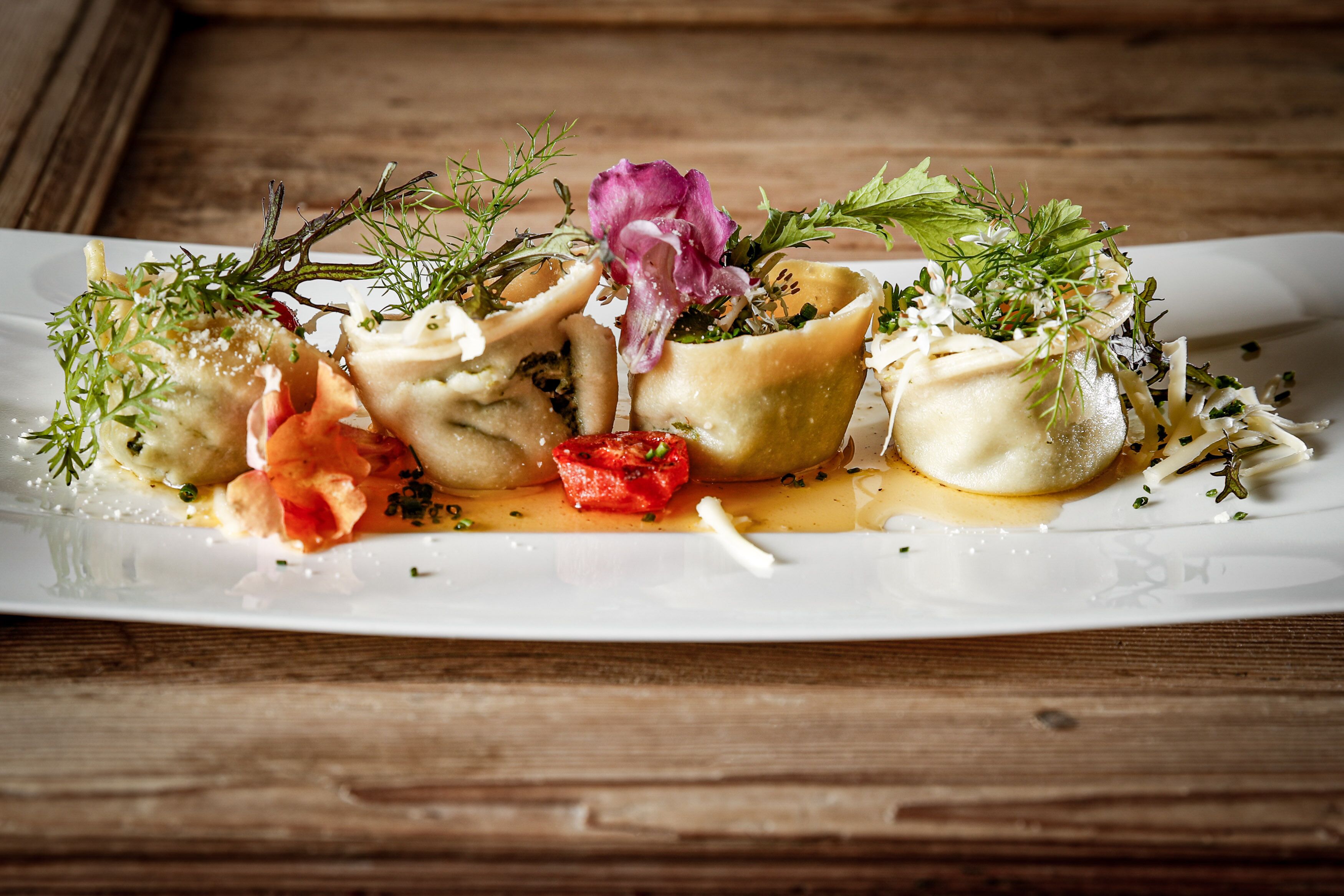 Un piatto di ravioli con diversi condimenti e salse.