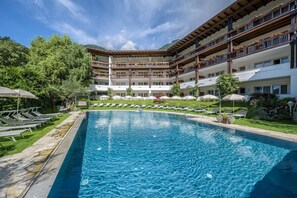 A hotel with a swimming pool, outdoor seating, and a mountainous backdrop. - Saltauserhof (San Martino in Passiria)