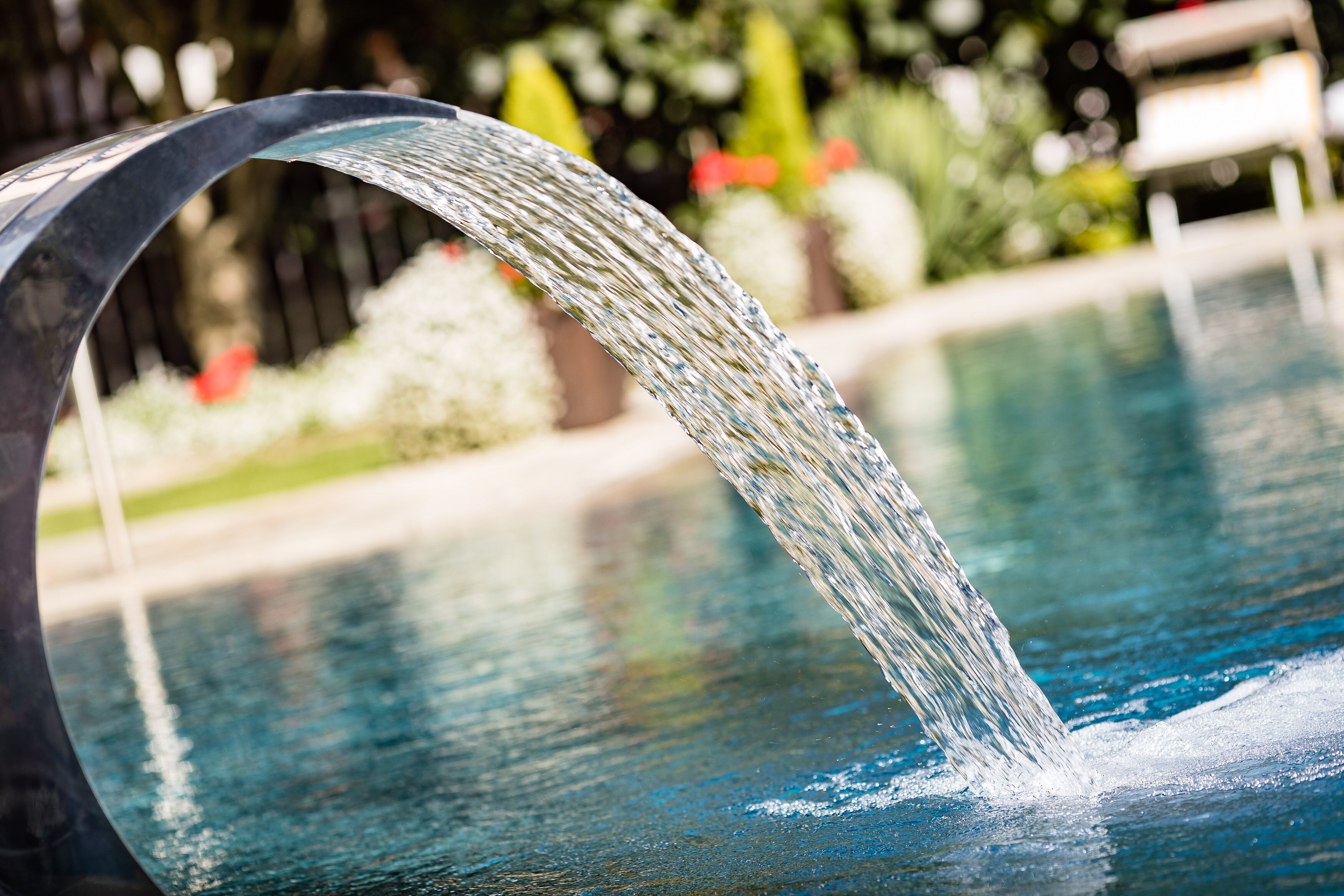 A water feature with a curved spout over a pool.