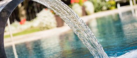 A water feature with a curved spout over a pool.