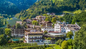 A hillside village with traditional European architecture, including multi-story buildings with balconies and a swimming pool area. - Saltauserhof (San Martino in Passiria)