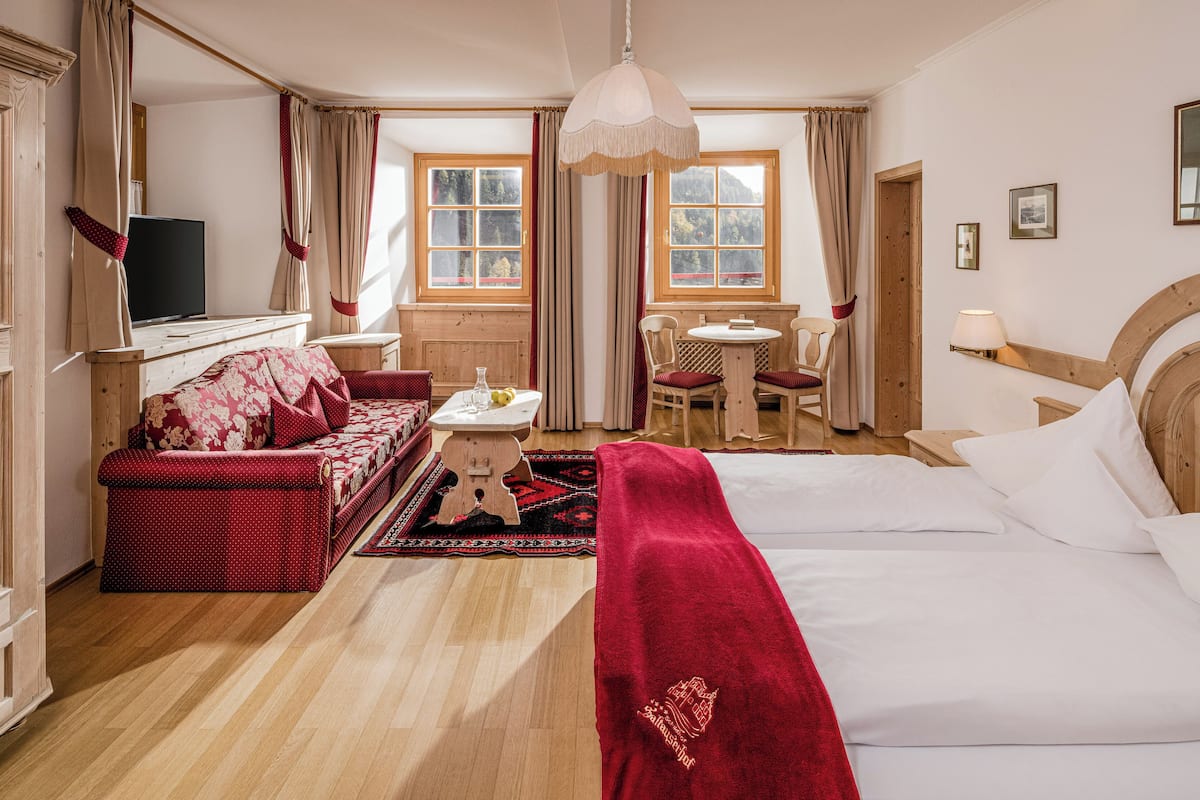 A hotel room with a bed, a sofa, a desk, a chair, and a television.