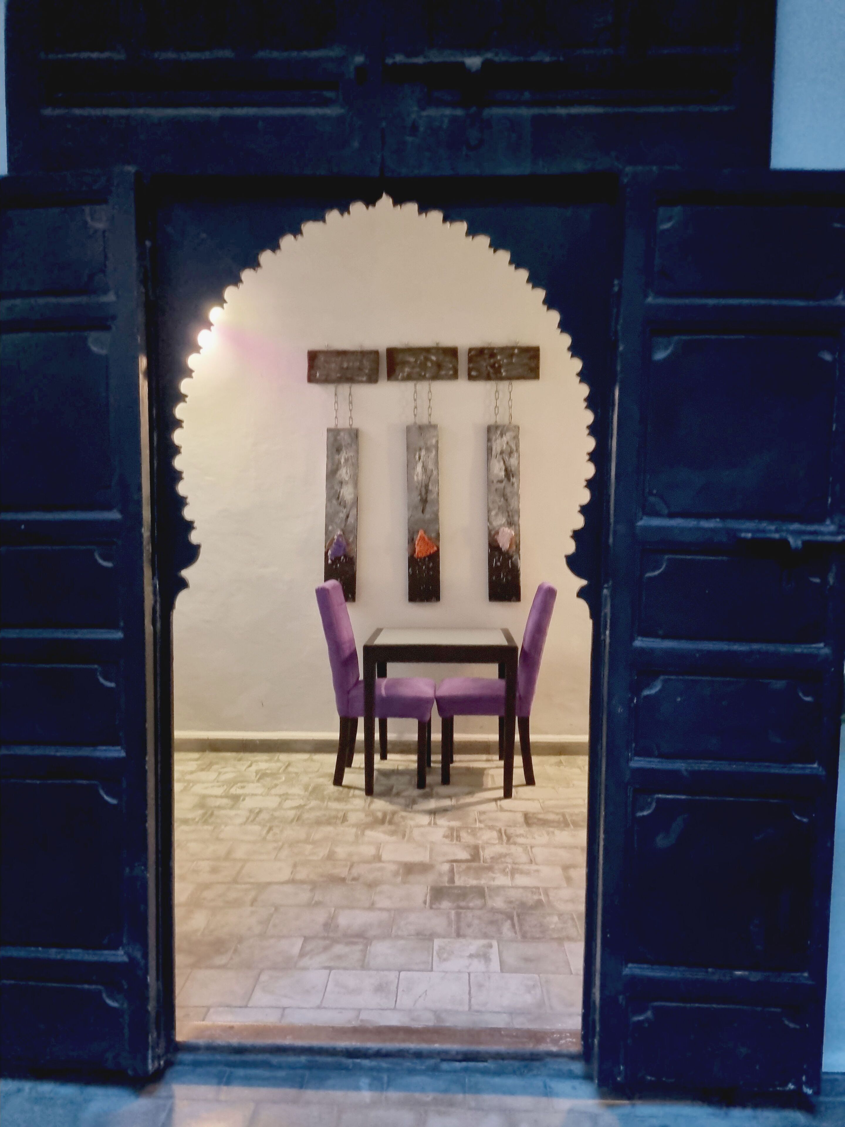 Un comedor con mesa y sillas, un muro decorativo y un suelo estampado.
