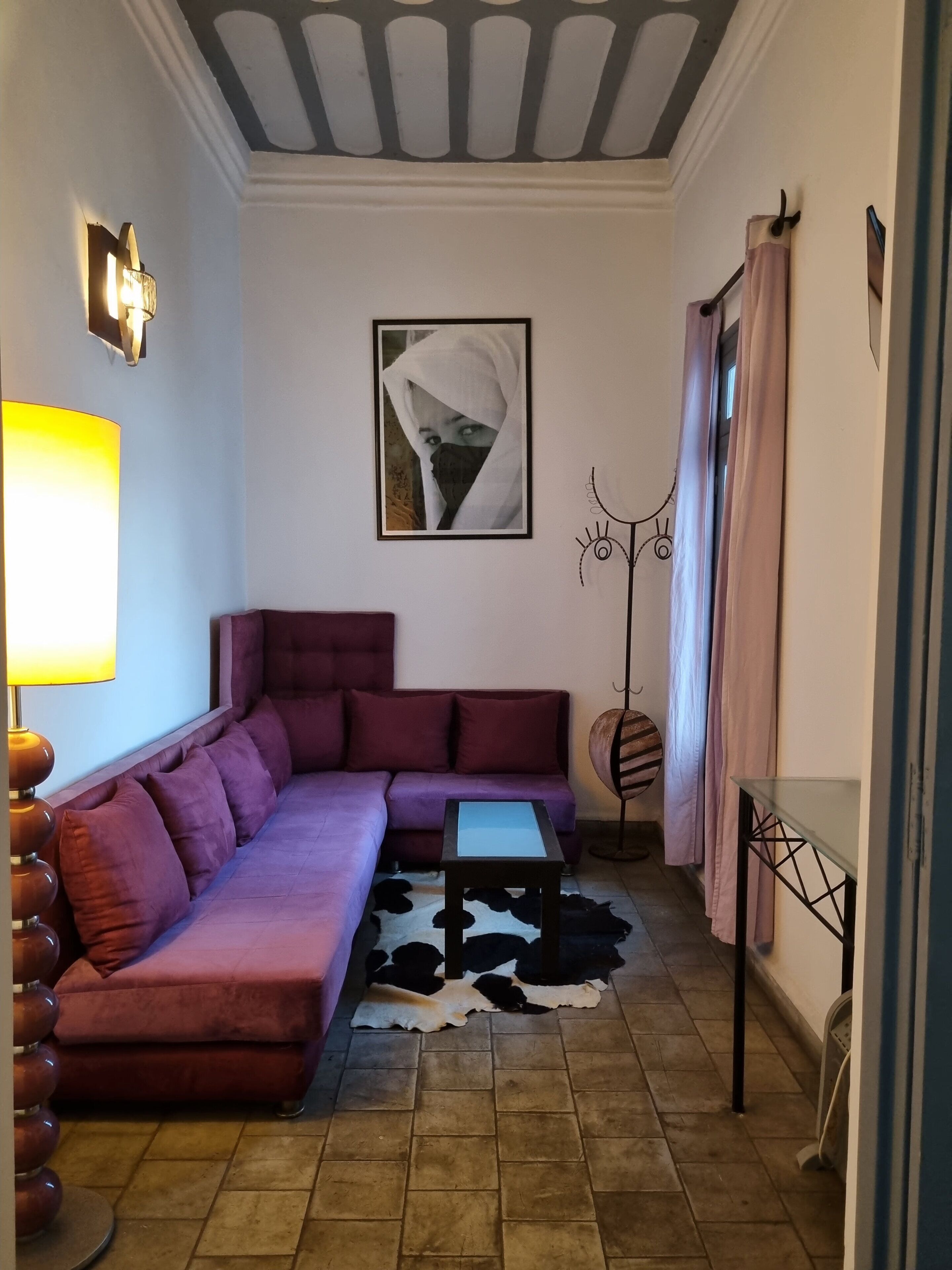 A living room with a sofa, a coffee table, a lamp, a wall-mounted picture, and a patterned rug.