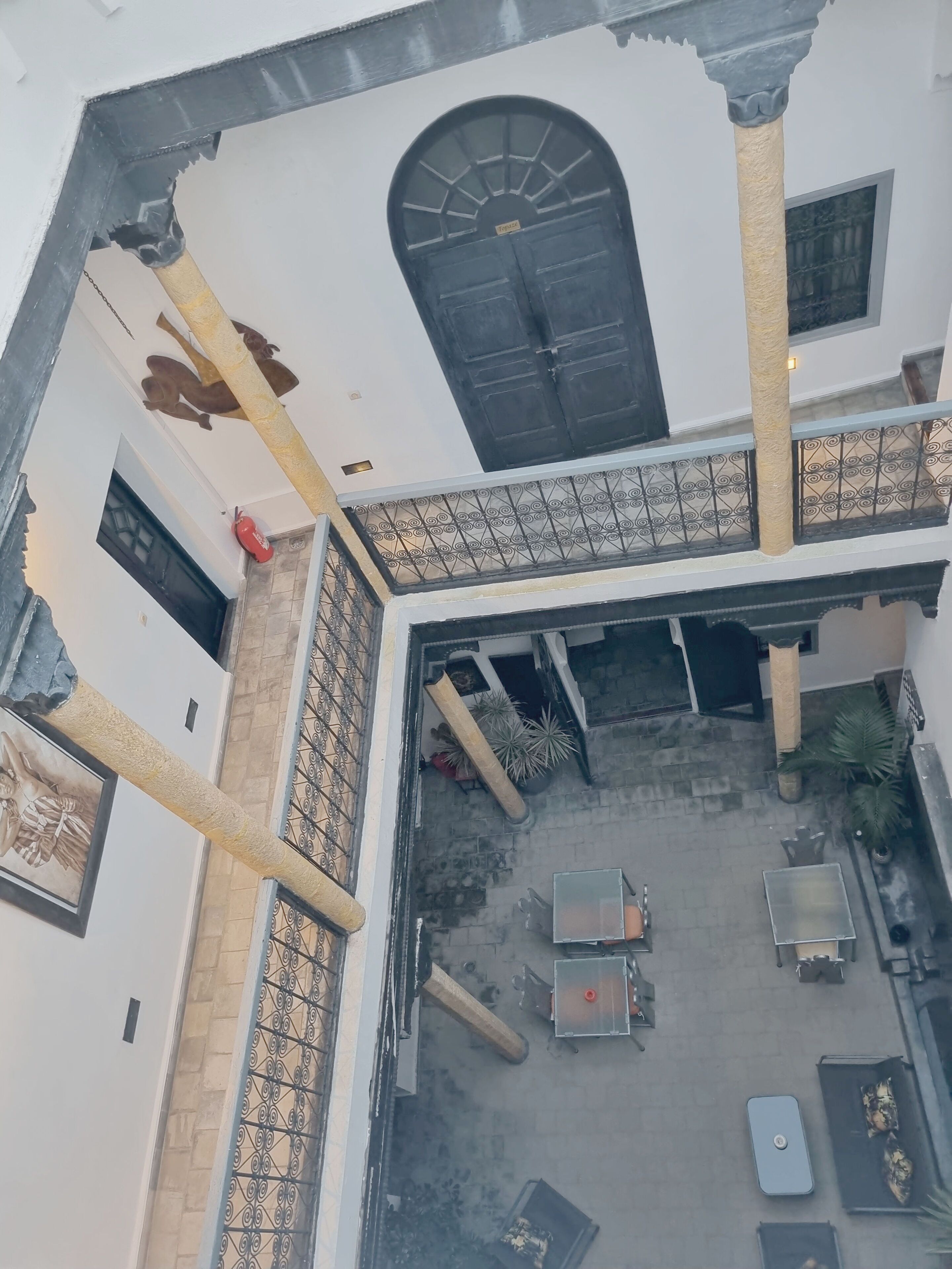 A courtyard with a central seating area, a black door, and a decorative ceiling.
