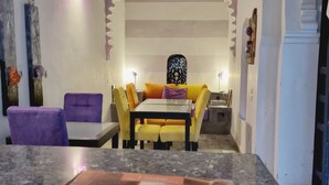 A dining area with a table and chairs, a decorative arch, and a poster on the wall.