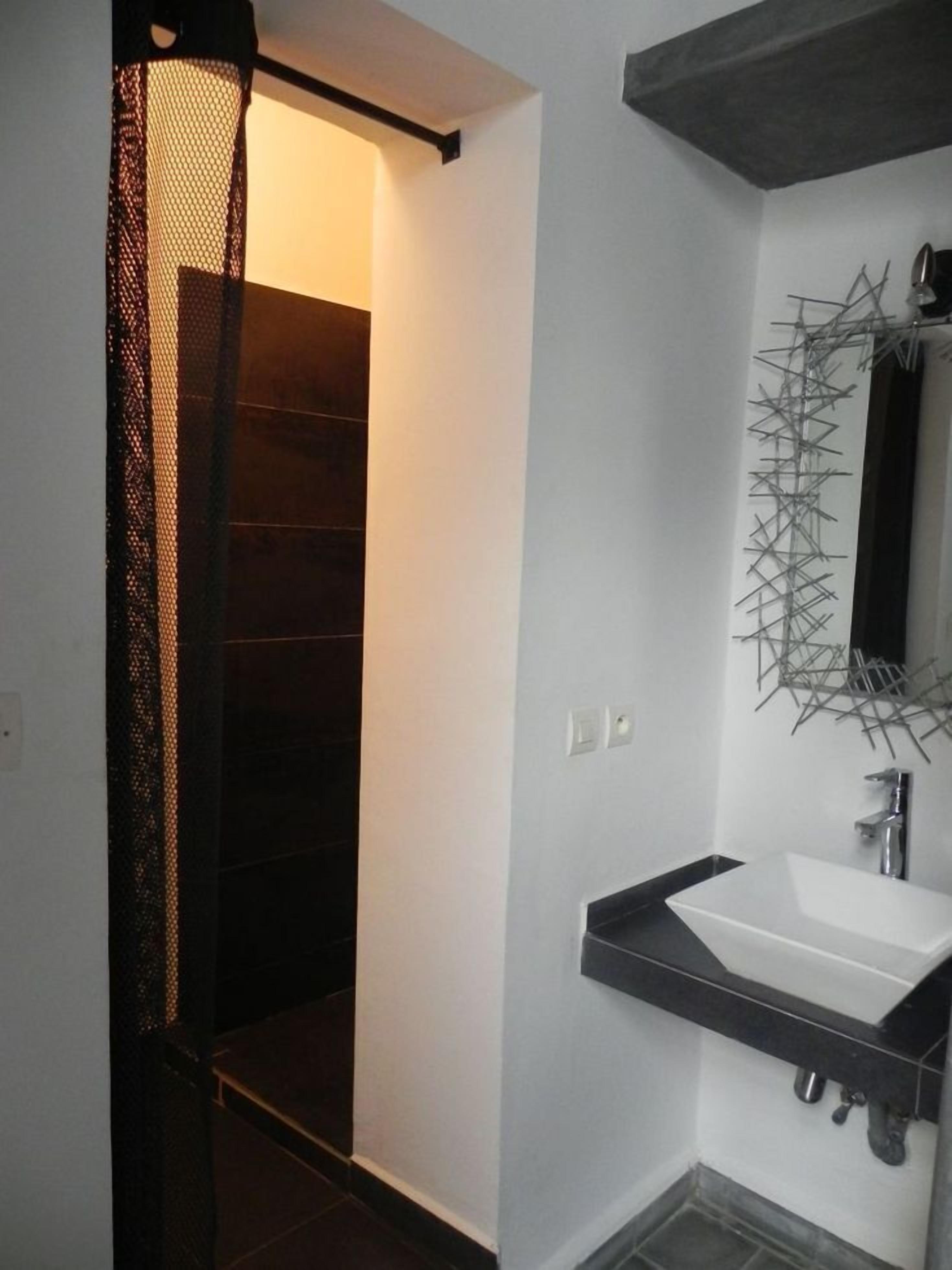 Un baño moderno con un lavabo blanco, encimera negra y un espejo decorativo.