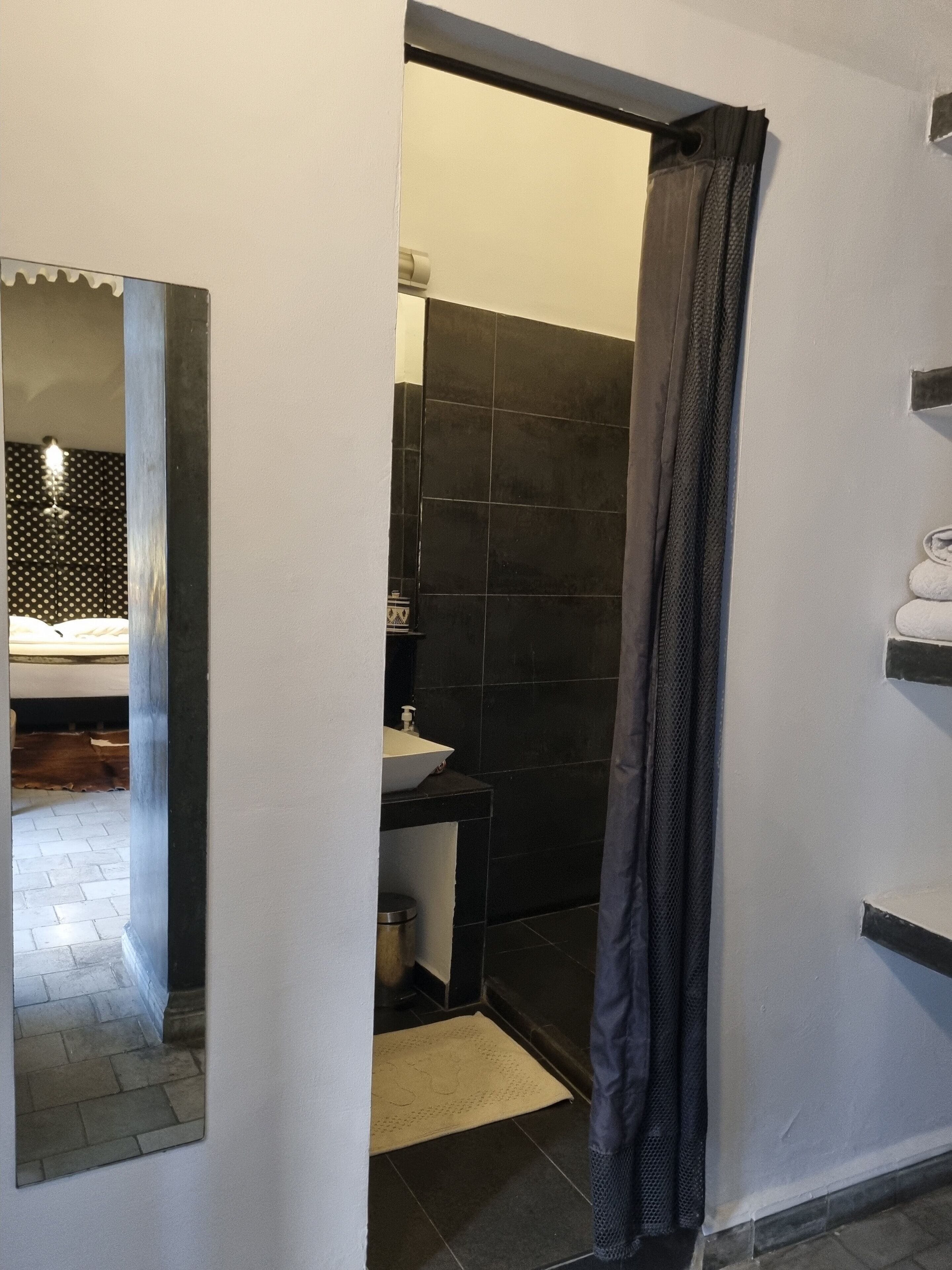 A bathroom with a white sink, dark tiles, and a shower curtain.