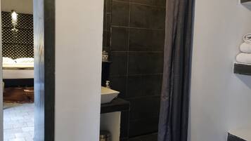 A bathroom with a white sink, dark tiles, and a shower curtain.