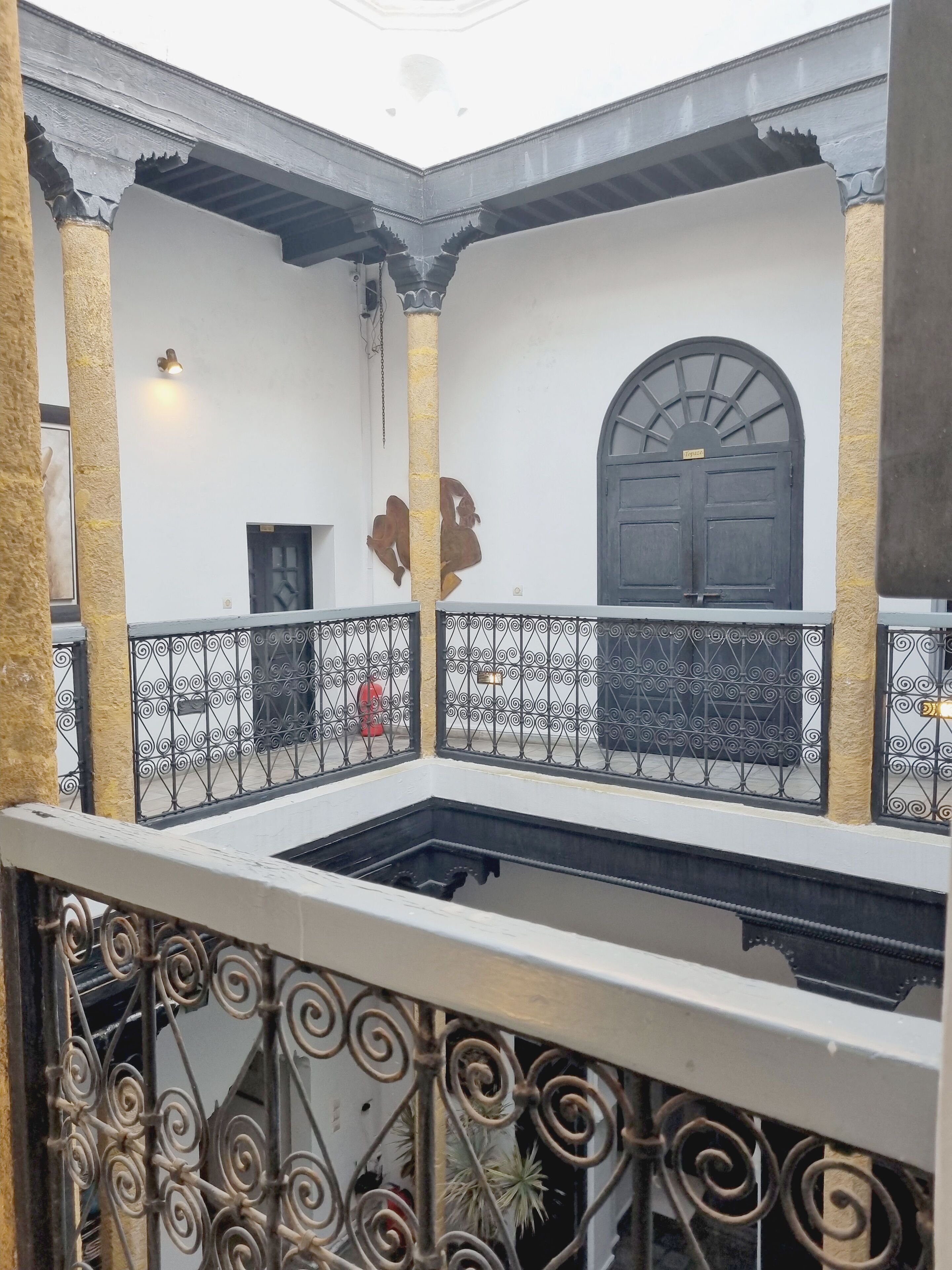 A courtyard with a central open space, a decorative door, and a metal railing.