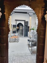 Una entrada con un arco tradicional que conduce a un patio con mesas y sillas.