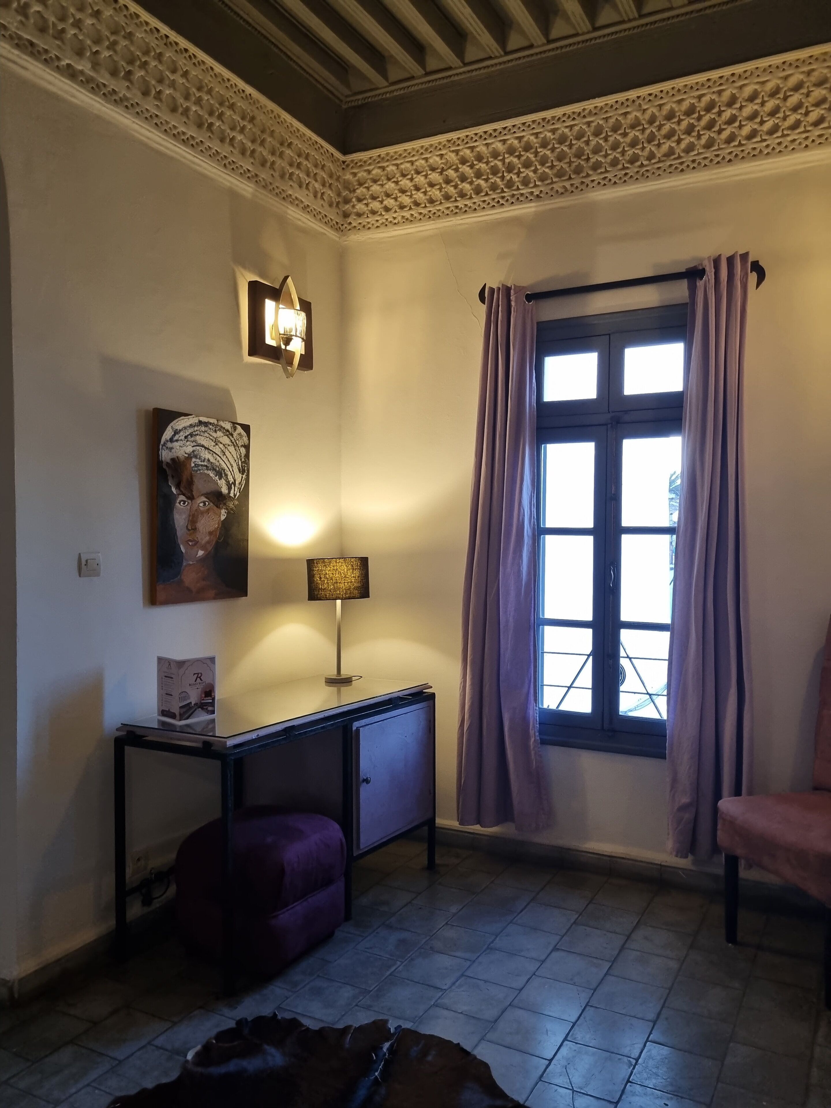 A room with a window, a lamp, a desk, a chair, and a sofa.