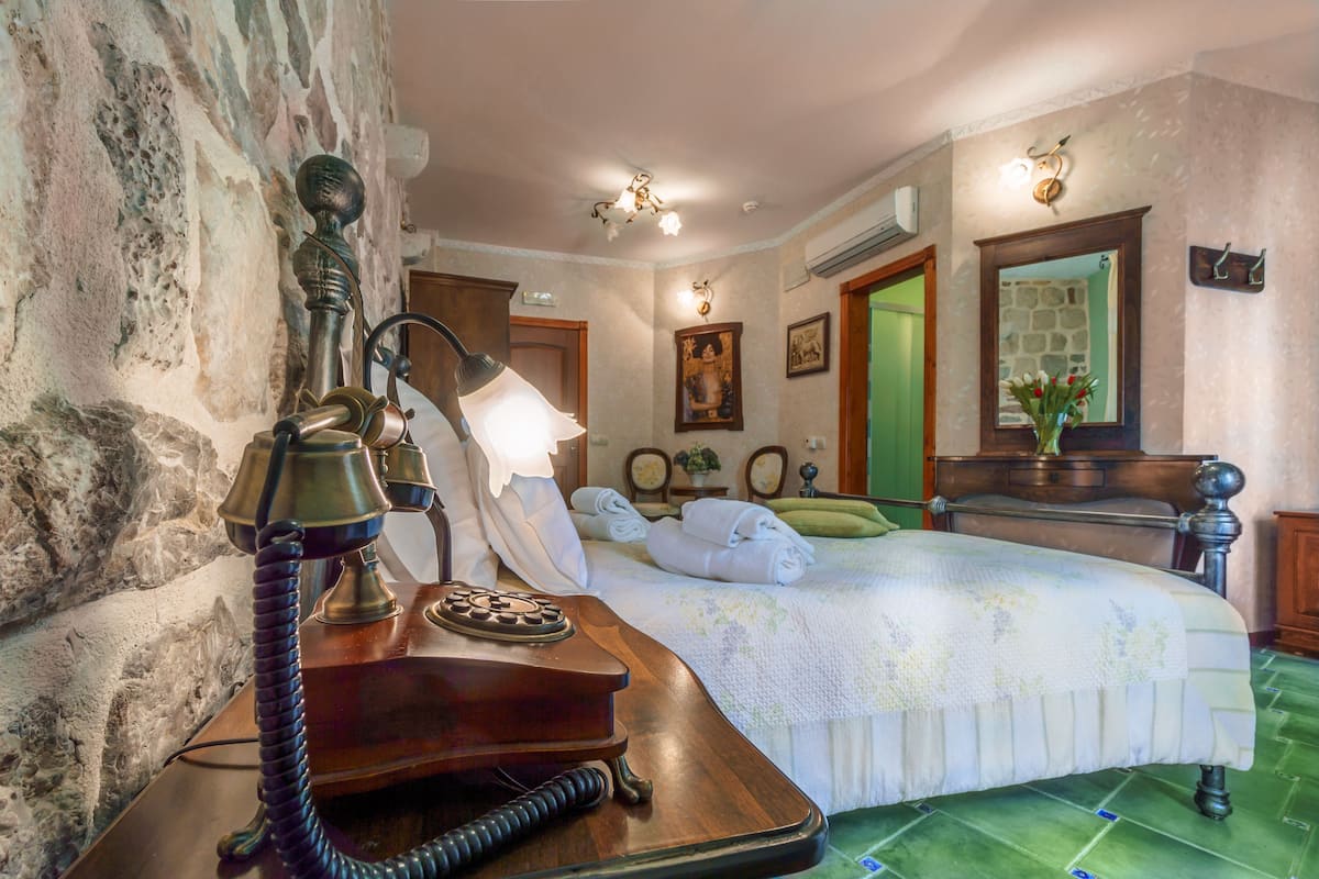 A room with a bed, a telephone, a mirror, and a wall with a textured pattern.