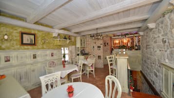 A rustic dining area with a brick wall, white wooden ceiling, and a bar area with bottles and decorations.