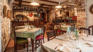 A restaurant with brick walls, wooden beams, and tables set for dining. - Hotel Monte Cristo (Kotor)