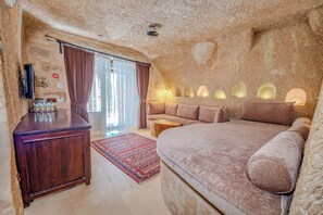 A cozy, rustic room with a large bed, a wooden desk, and a television.