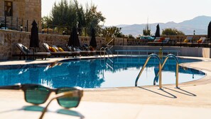 Une piscine avec des chaises longues et un mur en pierre.