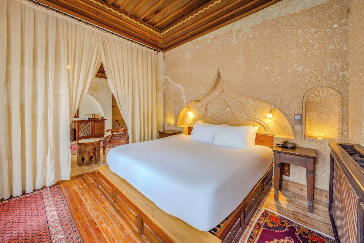 A spacious bedroom with a large bed, wooden headboard, and a decorative wall.