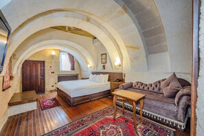 Une chambre à coucher avec un lit, un banc en bois et un canapé. Un tapis à motifs recouvre le sol.
