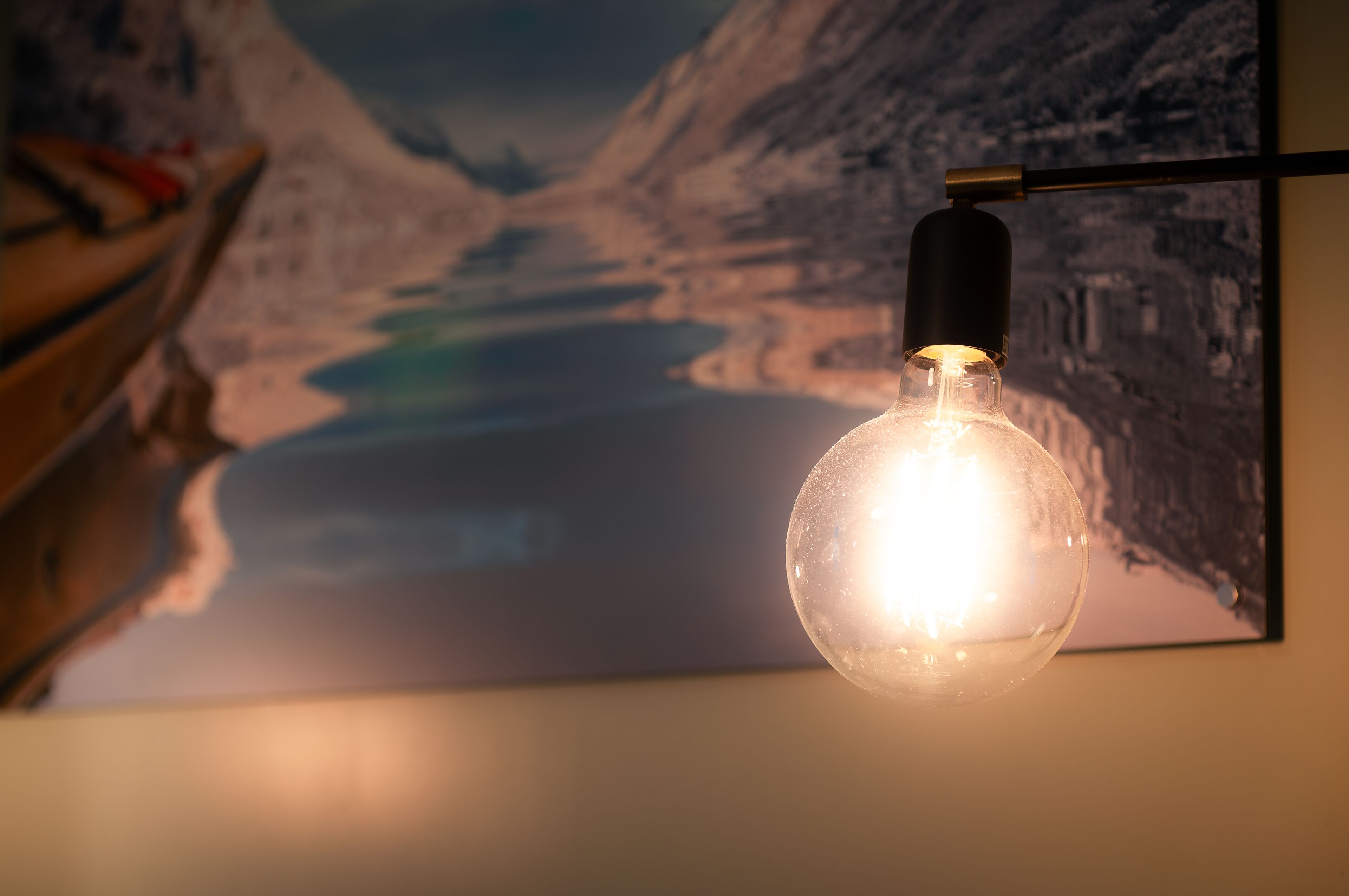 Une pièce avec un luminaire fixé au mur et un tableau représentant un paysage montagneux.