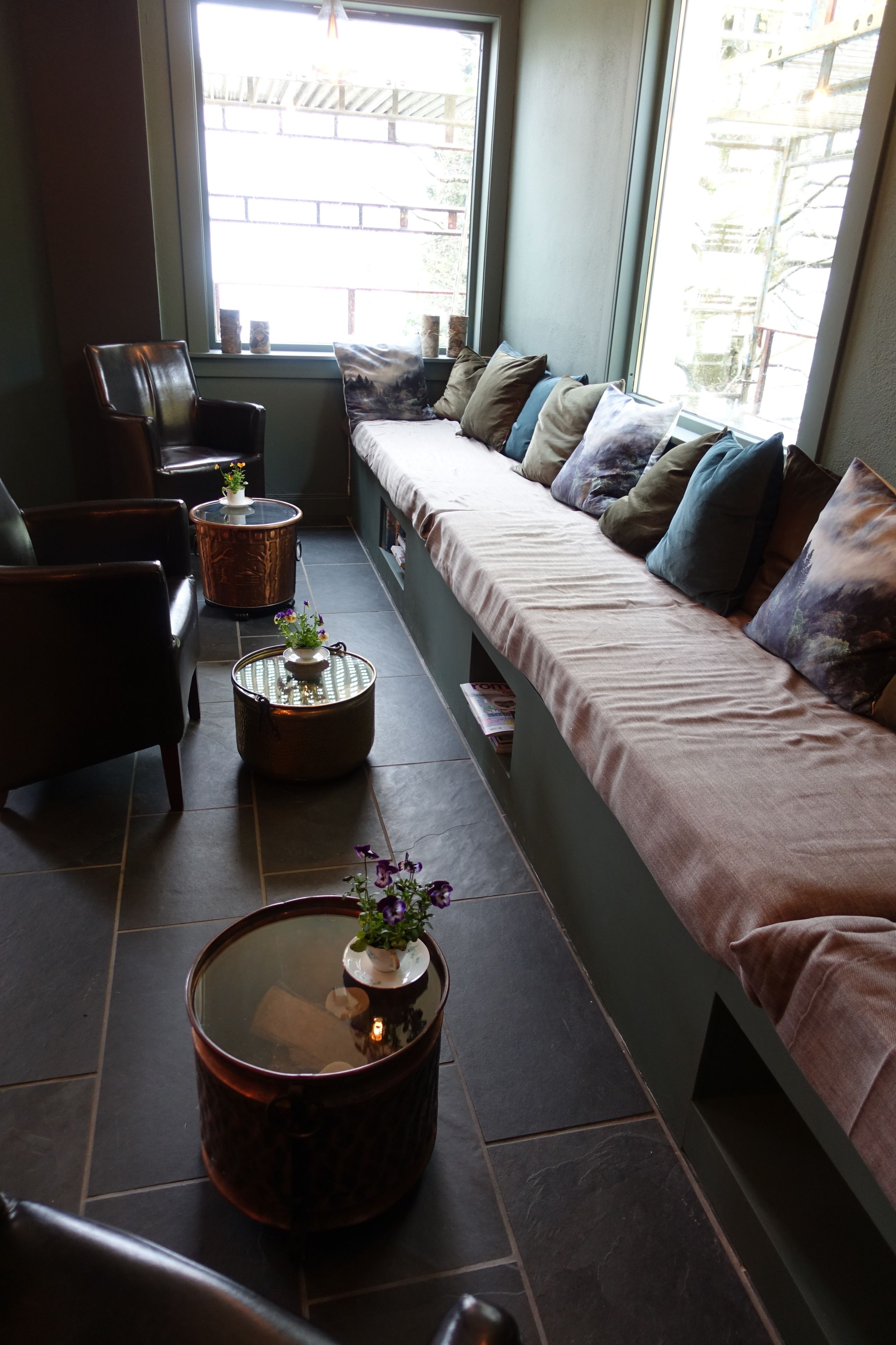 Angolo relax con divano, poltrone e tavolini rotondi decorati con piante.