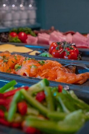A buffet with various dishes including salmon, vegetables, and meats.