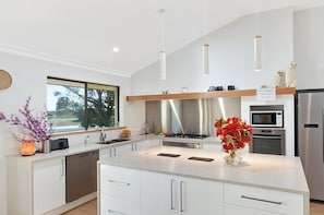 Una cocina moderna con una isla grande, electrodomésticos de acero inoxidable e iluminación colgante.