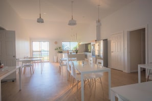 Una cocina amplia con armarios blancos, una isla central e iluminación colgante.