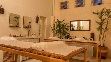 Experience tranquility in this serene spa room, featuring two massage tables, mirrors, and a calming atmosphere.