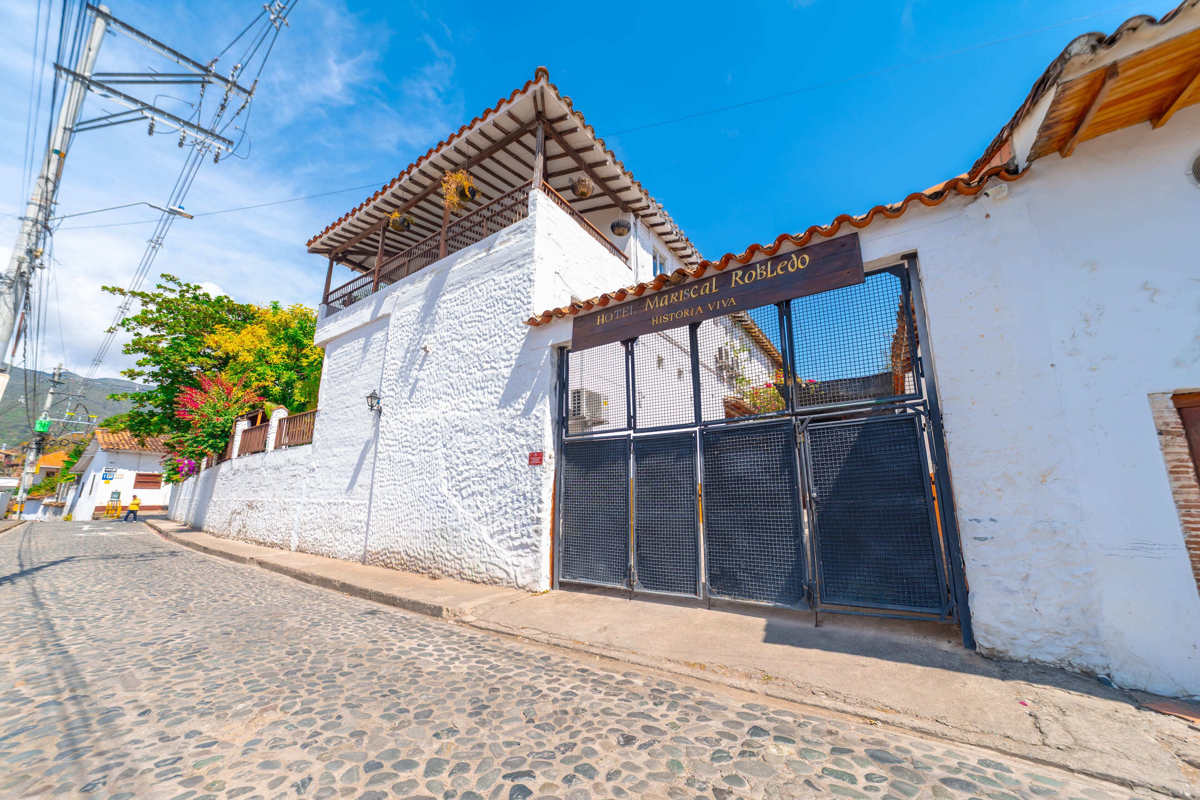 A cobblestone street leading to a white building with a sign reading "Hotel Mariscal Robledo Historia Viva".