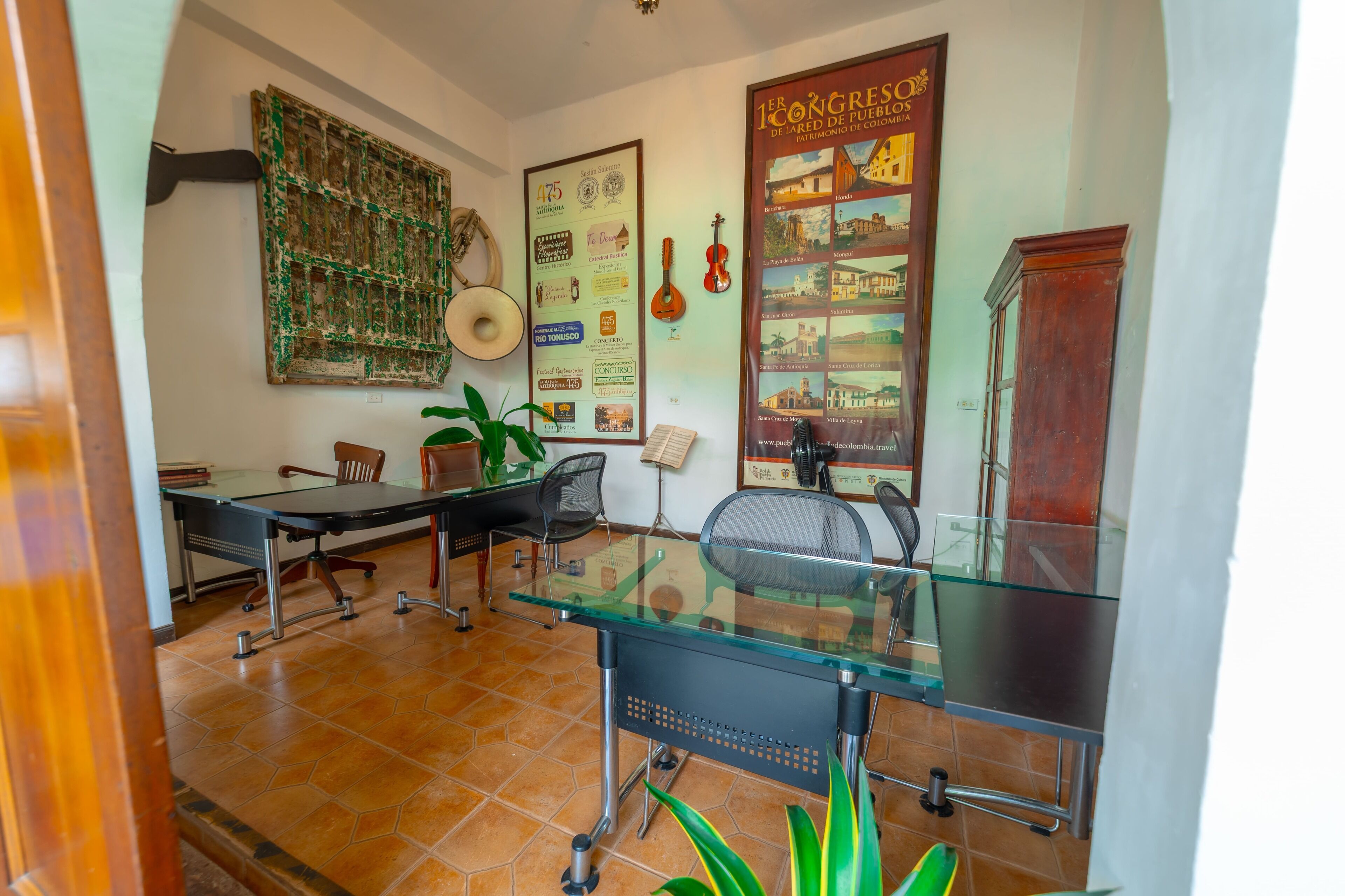 Une salle de conférence avec une table en verre, des chaises, une plante et une affiche accrochée au mur.