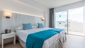 A modern hotel room with a large bed, a bedside table with a phone, and a view of the city through a large window. - BLUESEA Gran Playa (Sant Llorenc des Cardassar)