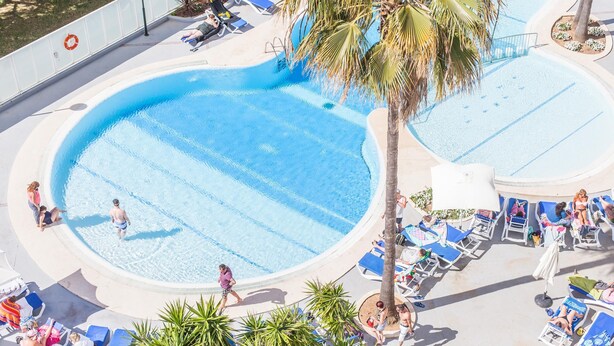A large, clear swimming pool with multiple lounge chairs and palm trees around it. - BLUESEA Gran Playa (Sant Llorenc des Cardassar)