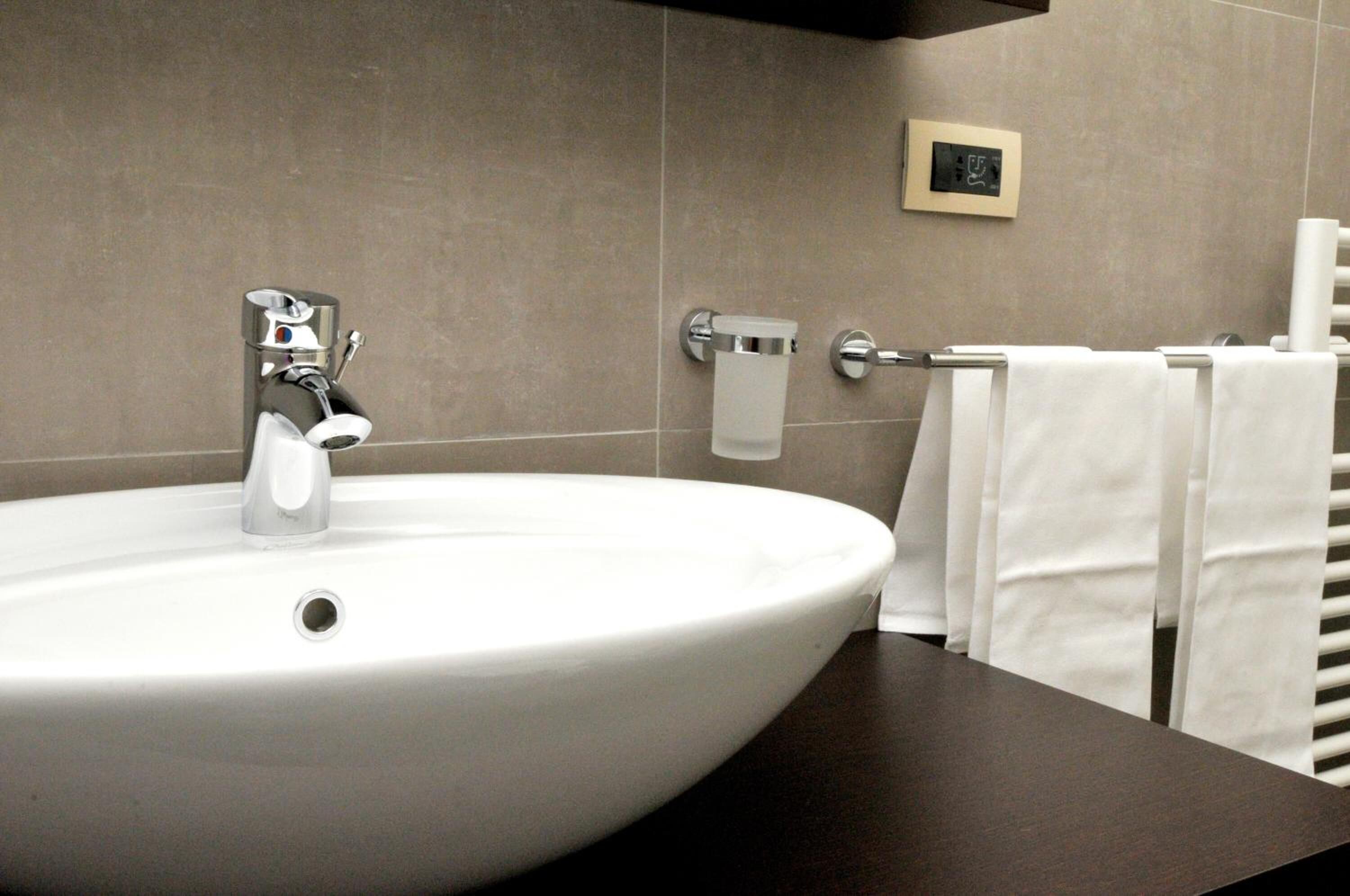 A bathroom with a white sink, a towel rack, and a toilet paper holder on the wall.