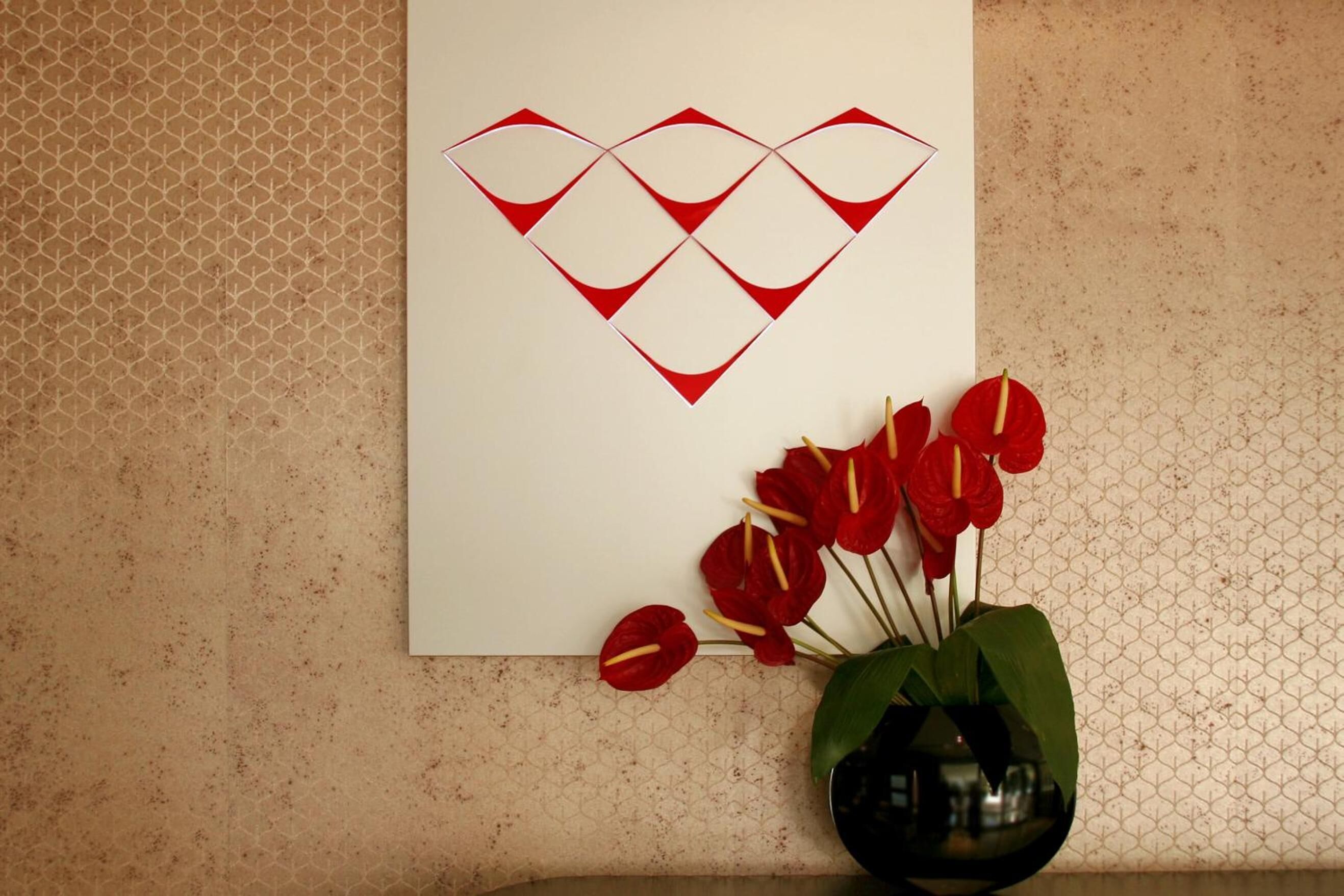 Una pared con un diseño geométrico y una obra de arte enmarcada.